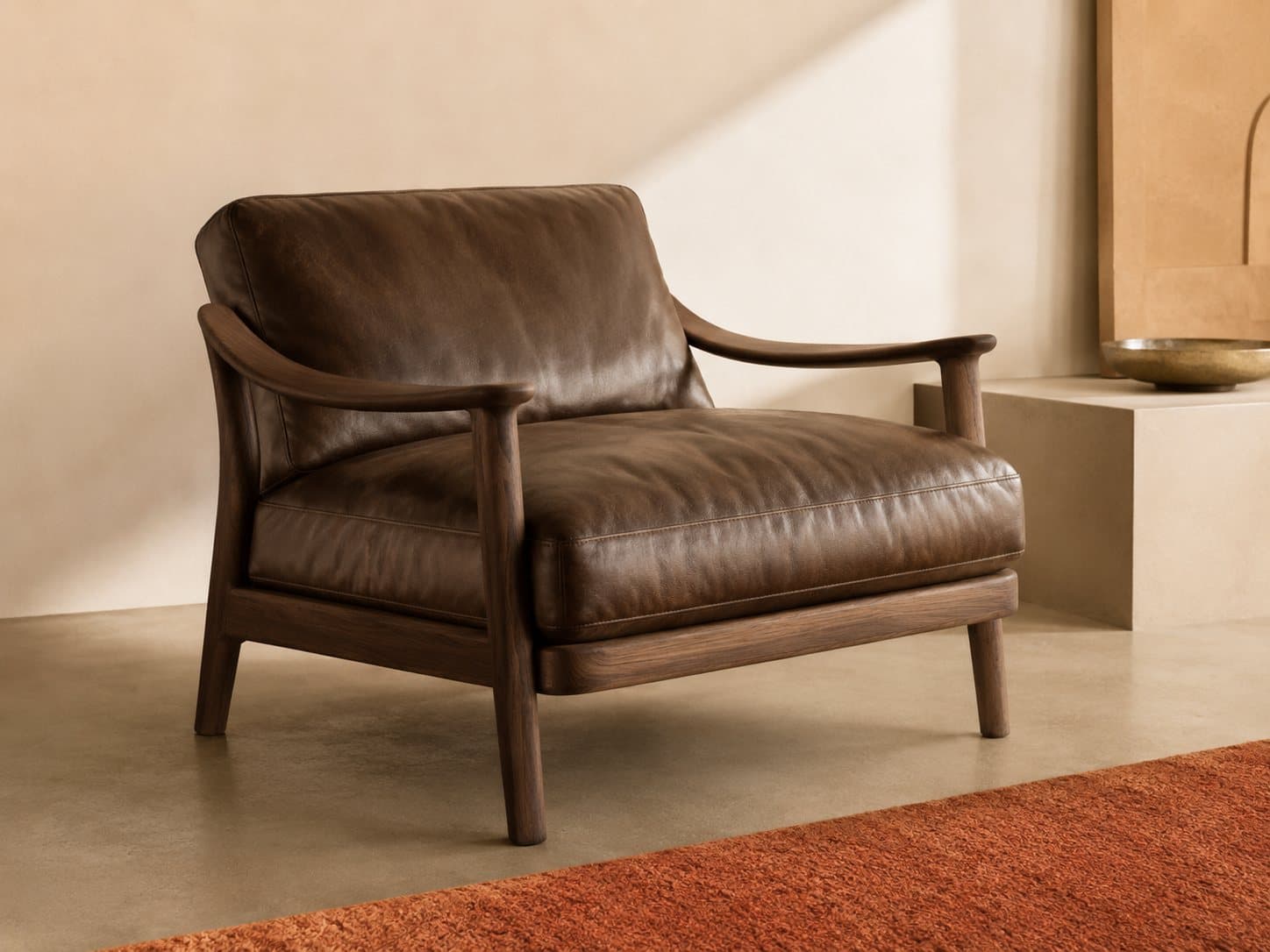 The Onda lounge chair: carved walnut frame cradling a deep leather seat, in raking light